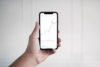 Person hält Smartphone und schaut sich Reporting an